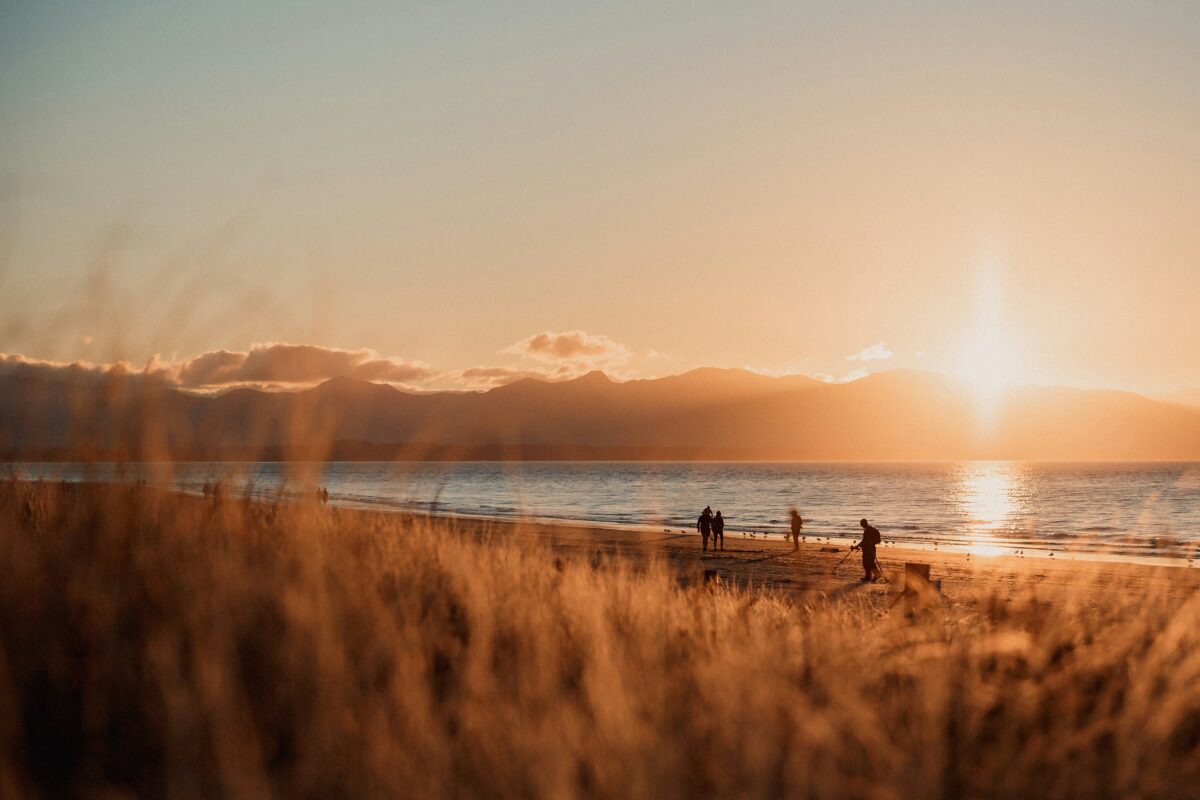 People walking along a beach at sunset